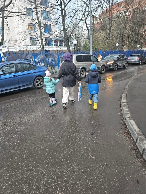 Adult, two children walk wet street in Khimki