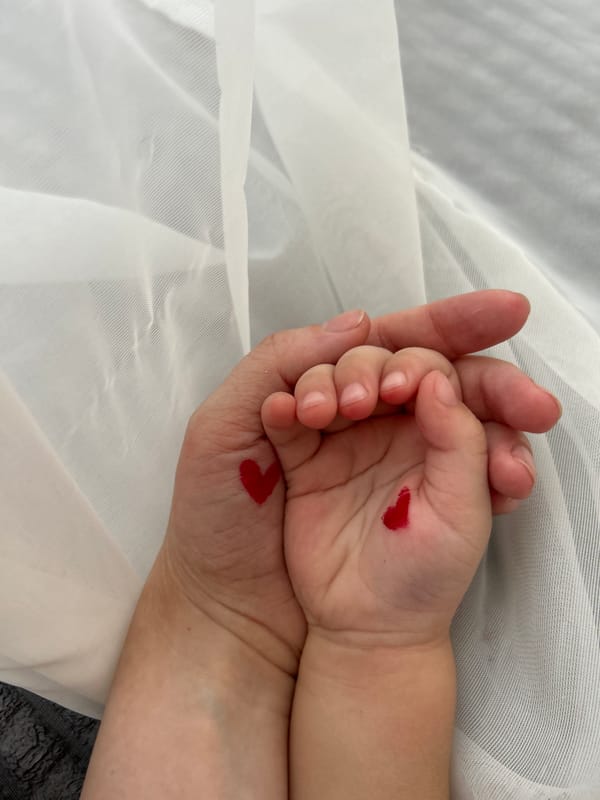 Adult, child hold hands with painted hearts in Ufa