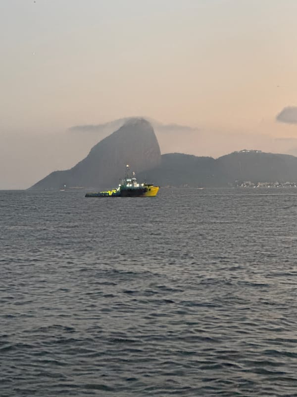 Drilling ship and tugboat off Niterói at twilight