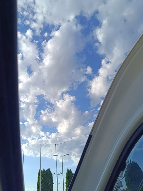 Blue skies and cumulus clouds through a vehicle window in Dobrich