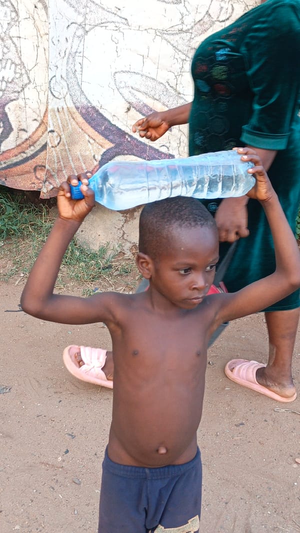Young males gather on dirt field in Onitsha during golden hour