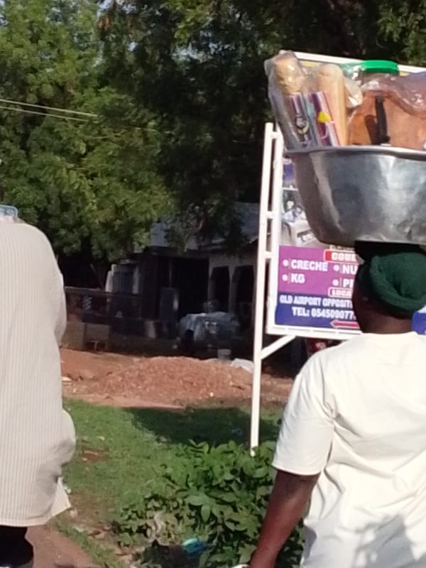 Person carries head load through dusty Tamale streets