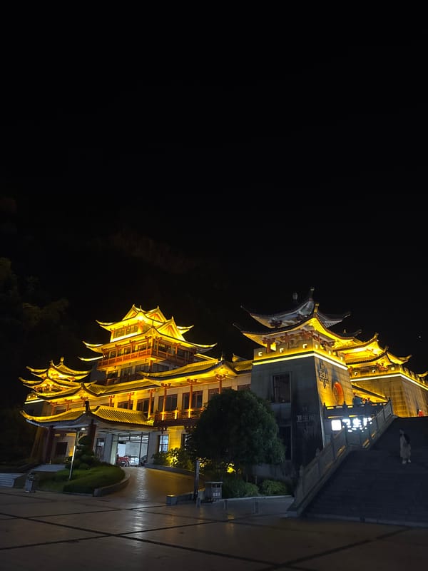 Illuminated traditional architecture glows against Yongding's night hills