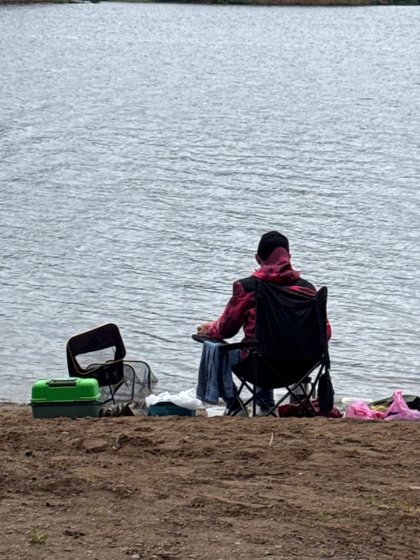 Person sits by industrial waterfront in Chaikovsky, Russia dawn