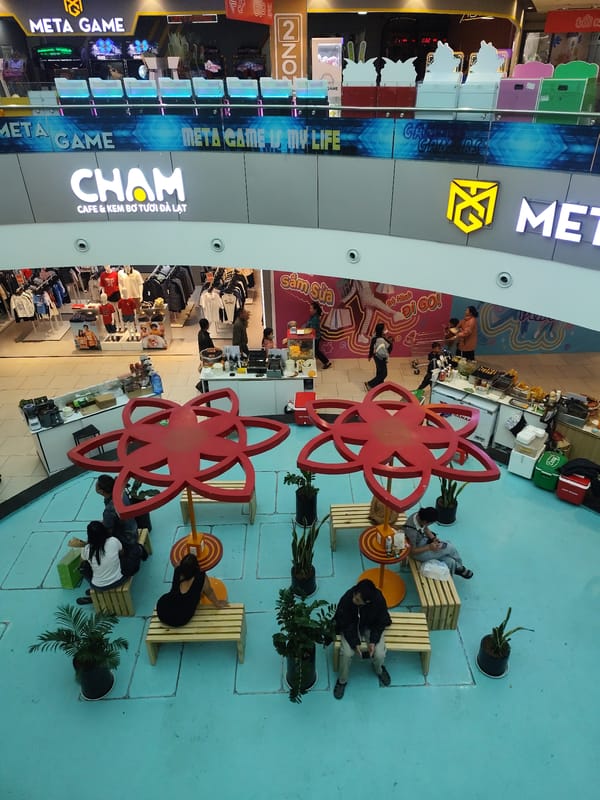 People gather near red flower structures in Da Lat indoor space