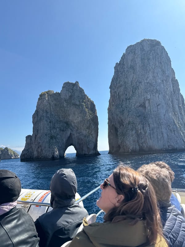 Tourist boat spotted near Faraglioni rocks in cloudy Capri morning