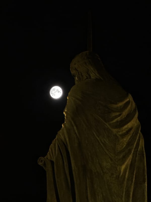 Full moon frames illuminated statue in nighttime Belgrade scene