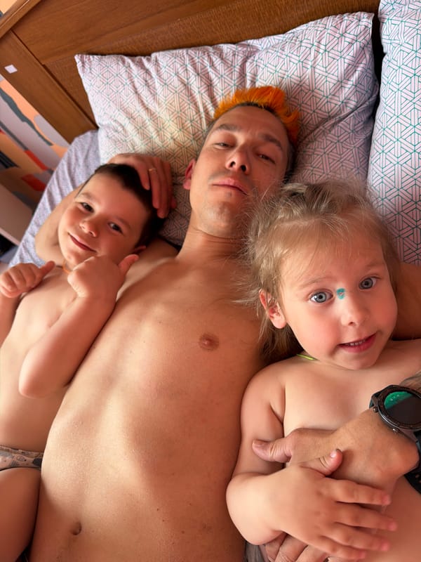 Three people rest together on geometric-patterned bed