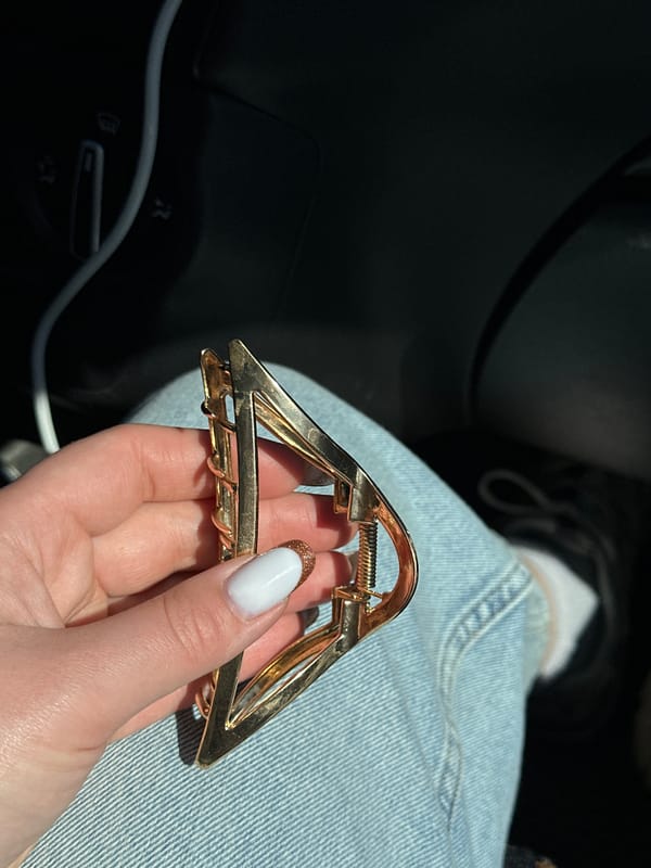 Person holds gold hair clip inside car in Russia
