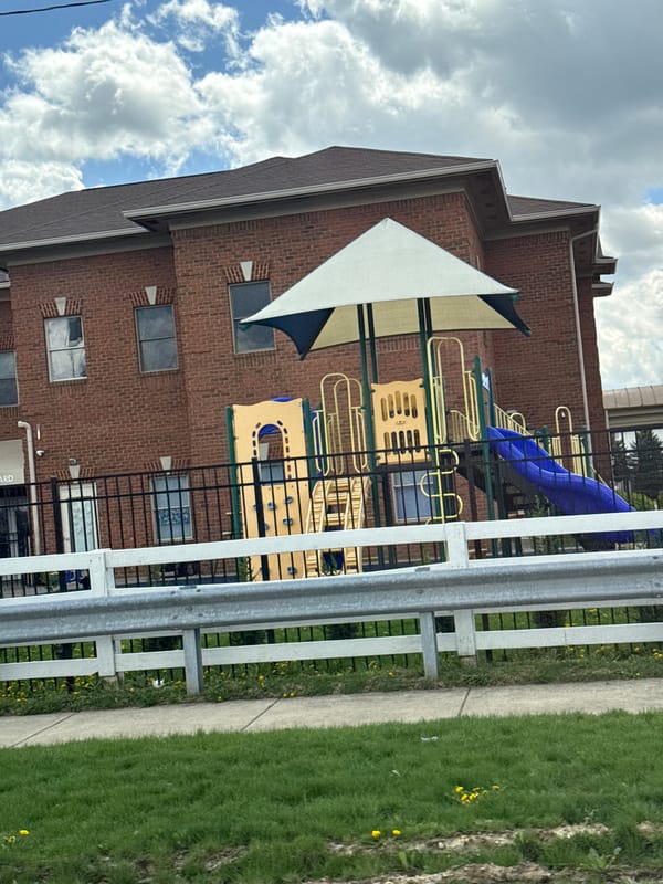 Colorful playground equipment observed near brick building in Columbus