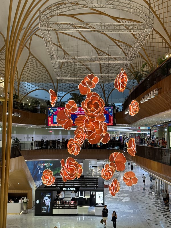 Inside a Wichit mall with flower light installations and retail stops