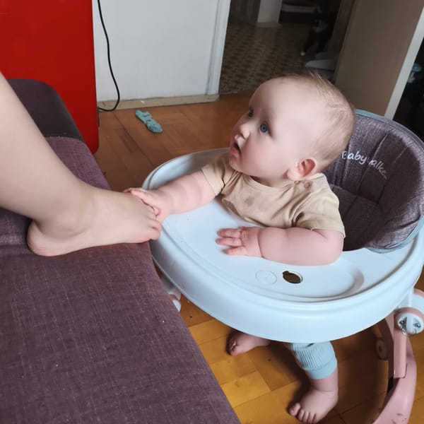 Infant in walker interacts with seated person