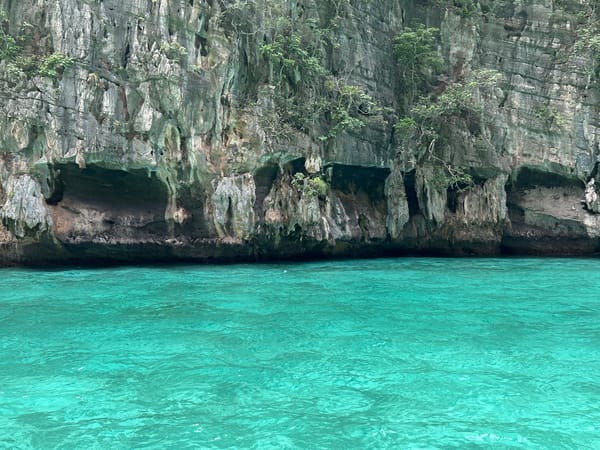 Long-tail boat drifts past limestone cliffs in Haad Yao
