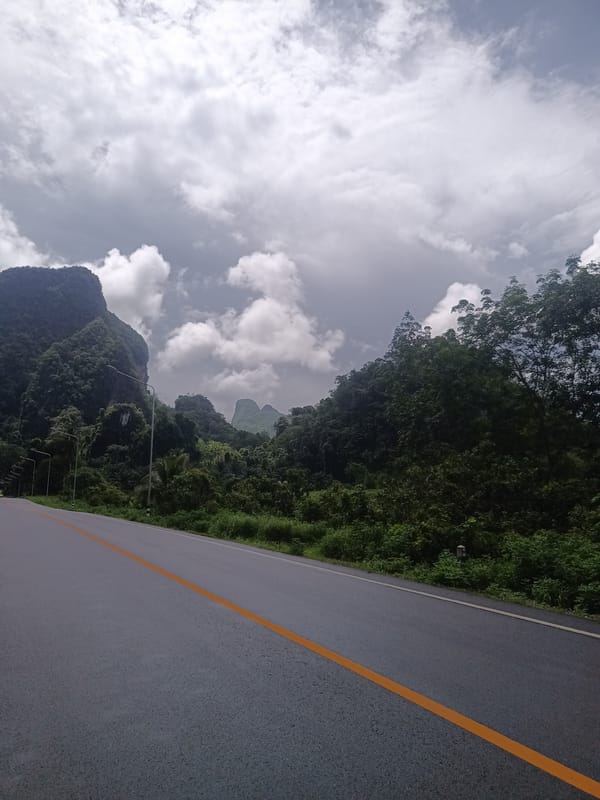 Woman photographs mountain scenery on rural Thai road