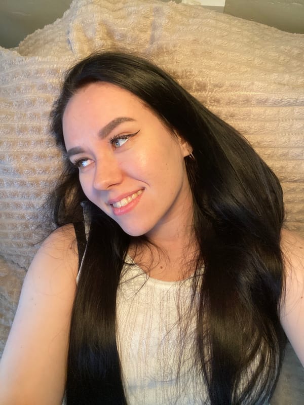 Woman photographed smiling on beige surface in Chaikovsky