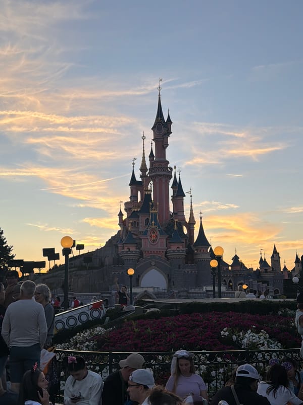 Sleeping Beauty Castle glows under a warm dusk sky
