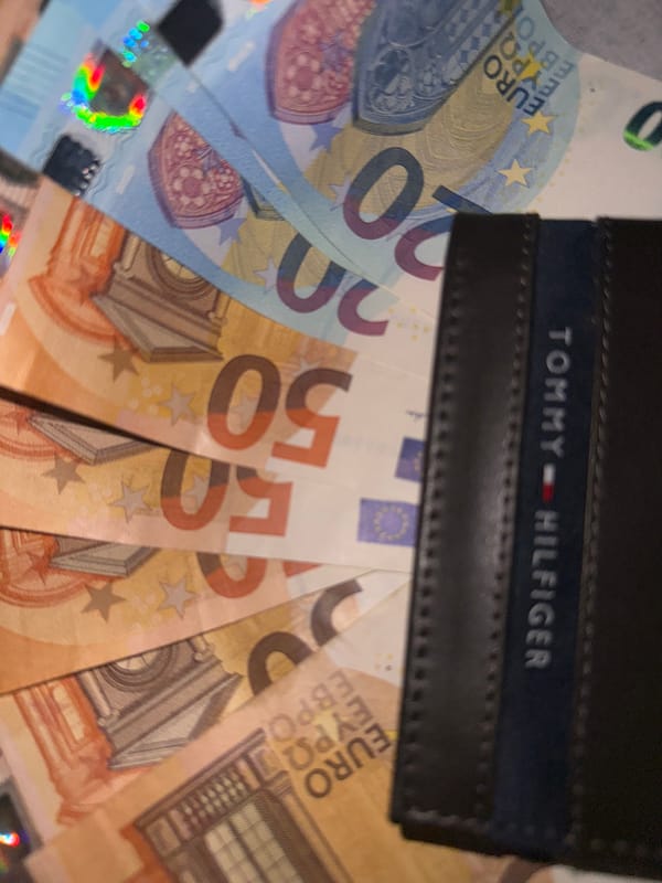 Tommy Hilfiger wallet photographed with scattered Euro banknotes