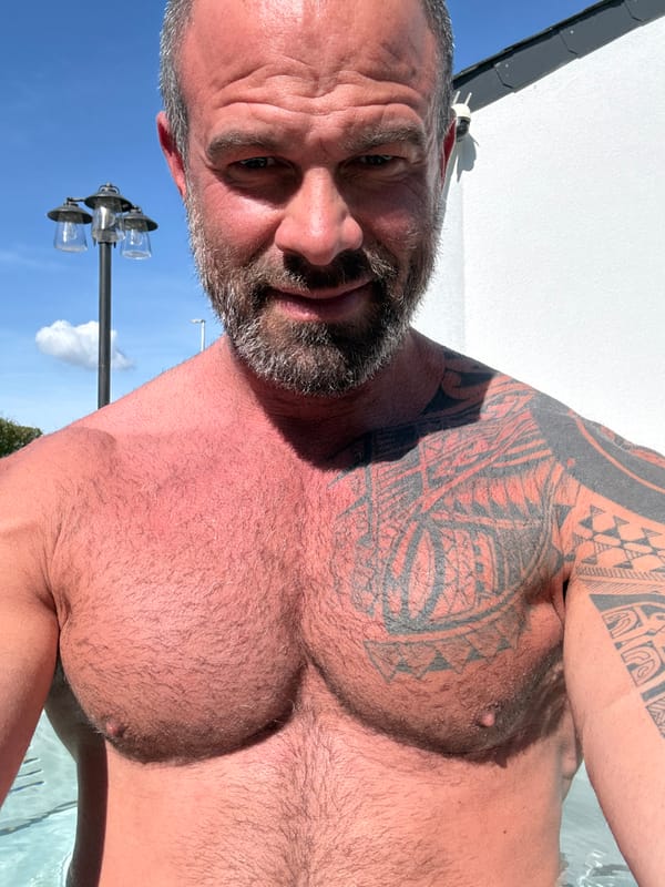 Shirtless man photographed in outdoor pool setting in Belgium