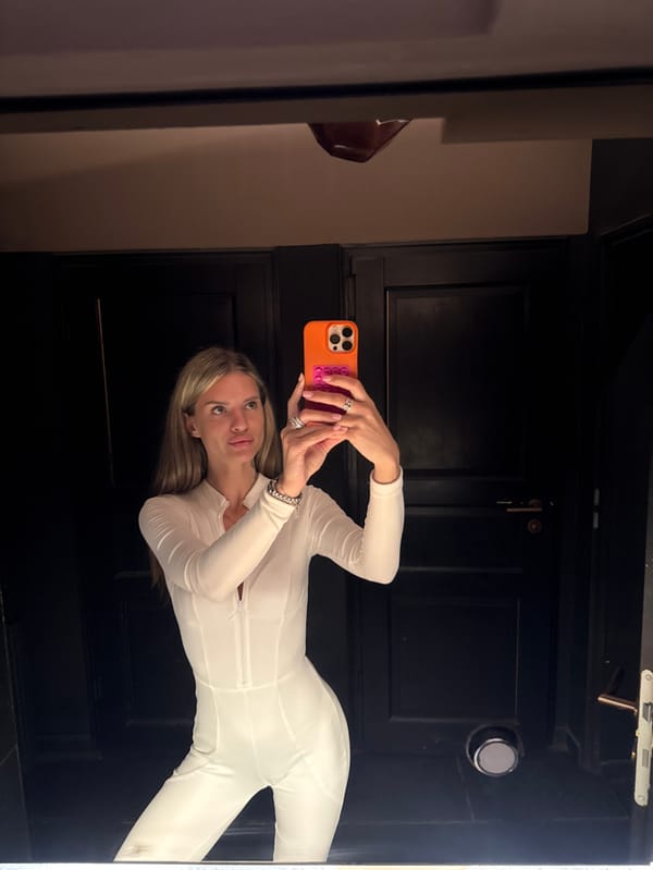 Woman takes mirror selfie in white jumpsuit in Berlin