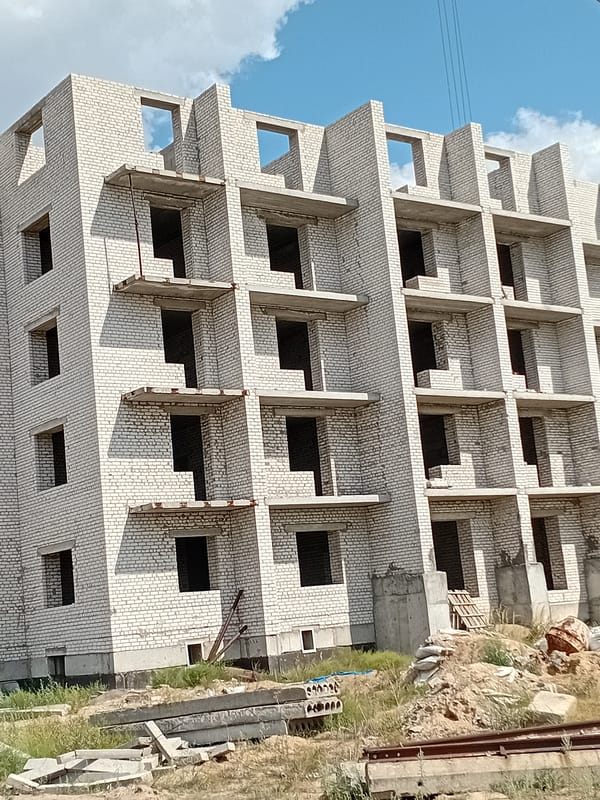 White brick building mid-construction, facade and floors still unfinished