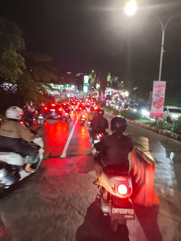 Heavy motorcycle traffic crawls through rainy Depok streets