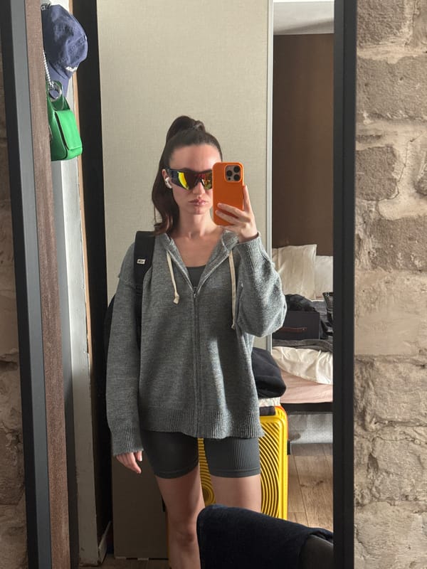 Woman photographed in mirror reflection holding orange phone in Tel Aviv