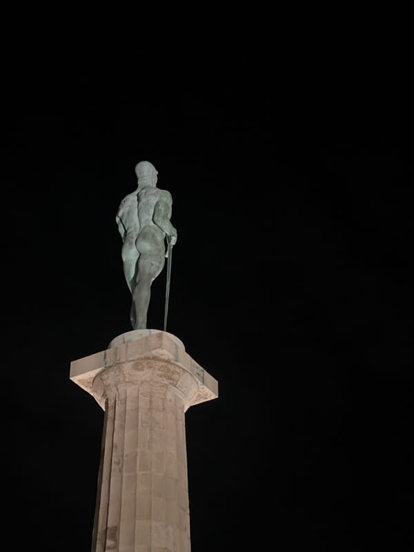 Person holds Patrick Star plush near sword statue in Belgrade