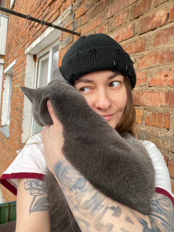 Person with tattoos holds gray cat in Votkinsk