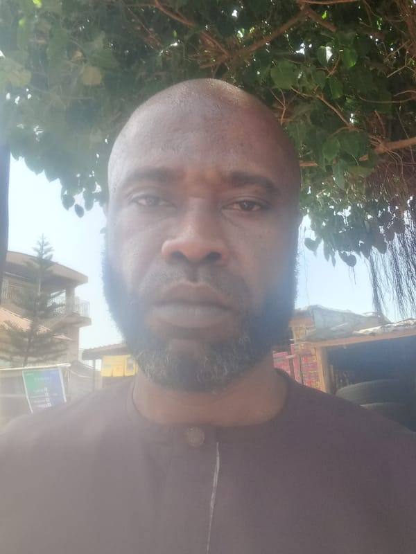 Man in purple shirt observed near palm trees in Nigeria