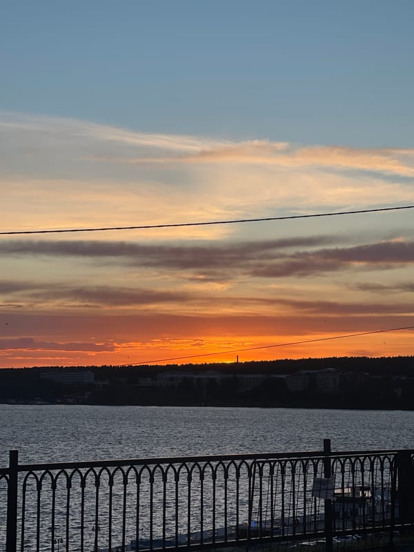 Sunset gathering documented at urban waterfront with carnival attractions