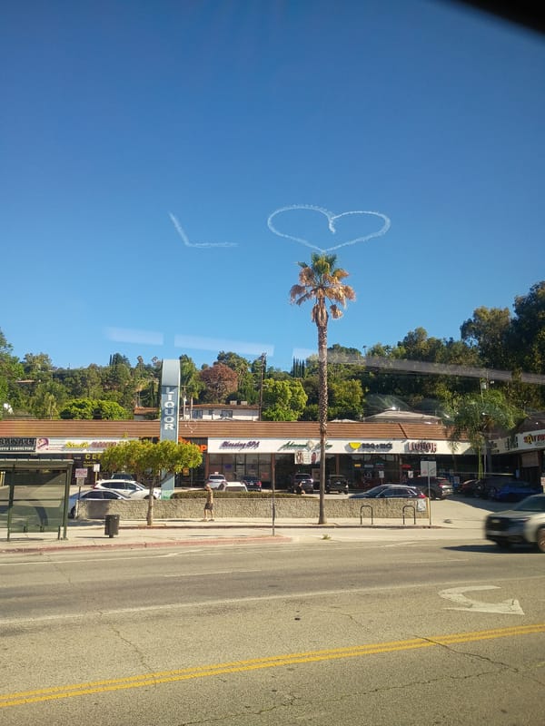 Skywriting contrails form a heart above Los Angeles streets