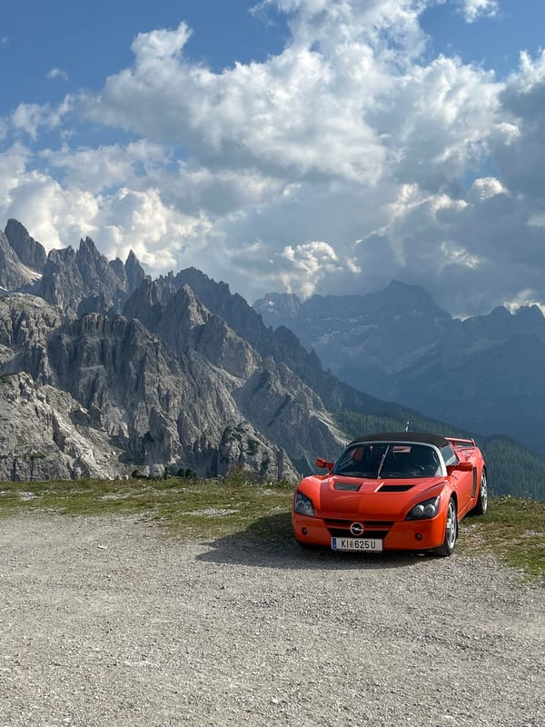 Orange Opel GT parked against sweeping mountain valley views
