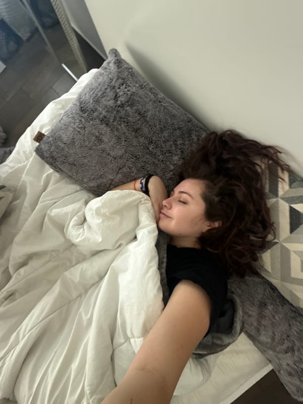Woman rests in bed, makes peace sign gesture