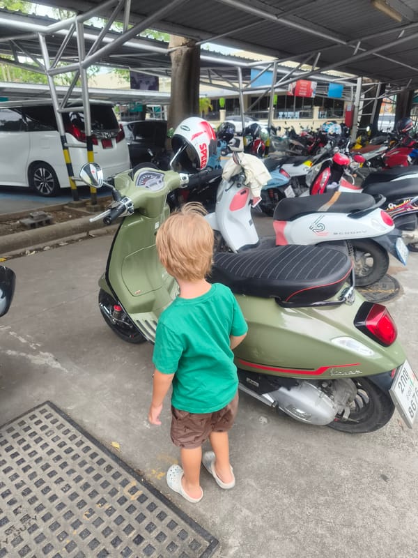 Child examines green scooter at Thai commercial complex
