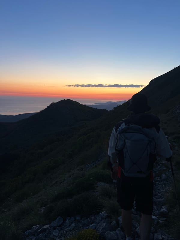 Hiker watches sunset from mountain slope in Dolovi, Montenegro