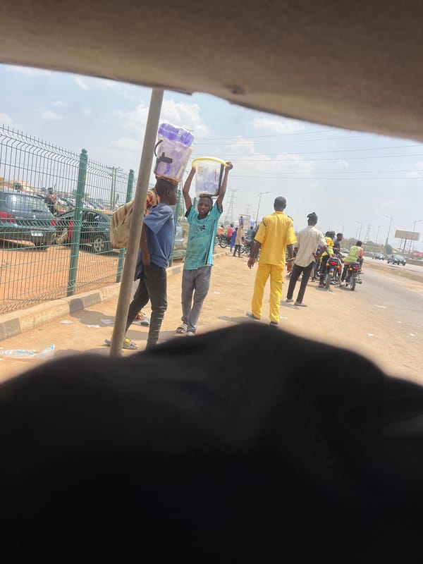 Street vendors carry goods along Nigerian village roads