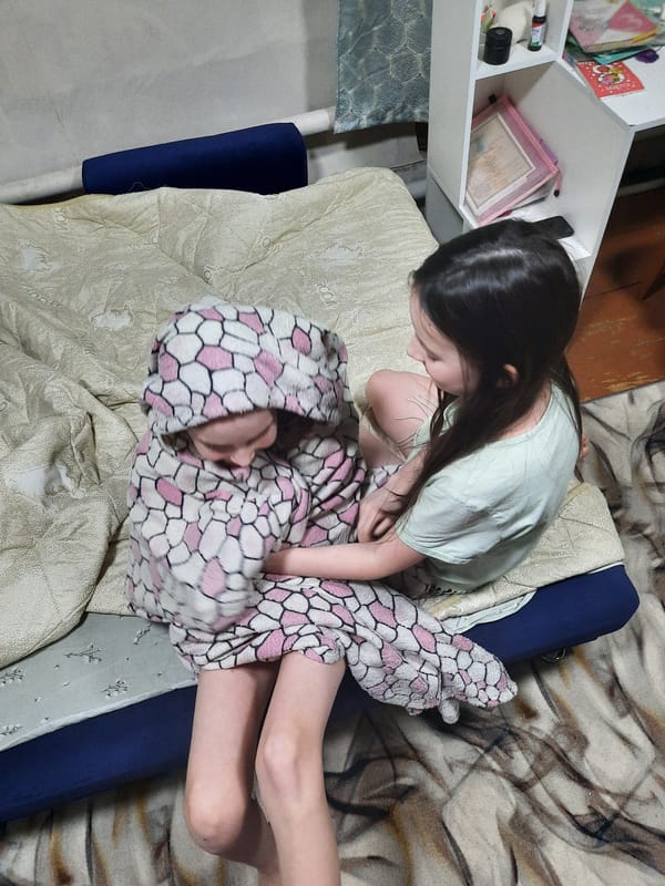 Two girls play together on bed in Russian home