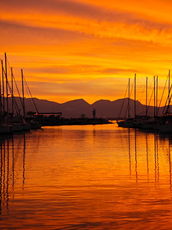 Sunset documented at Finike marina with sailboats and lighthouse