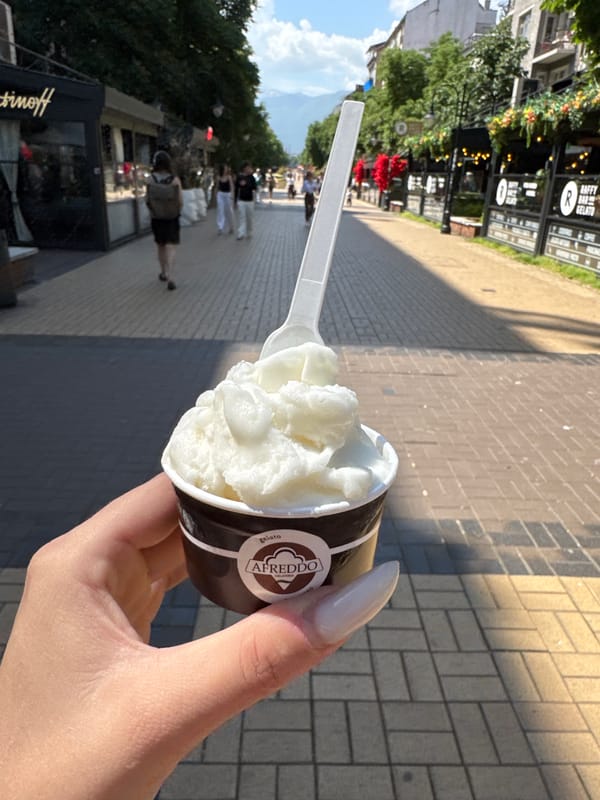 Person enjoys Alfredo gelato on street morning scene