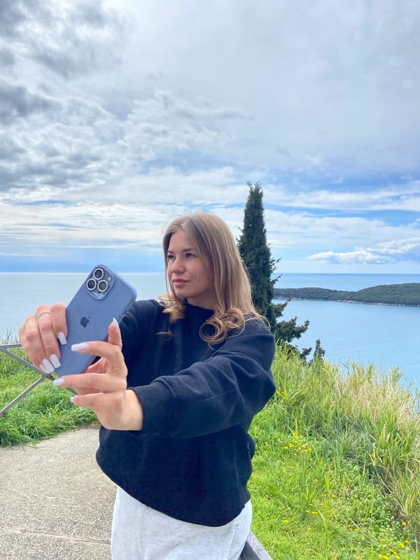 Woman photographs scenic coastal views during Montenegro overlook visit