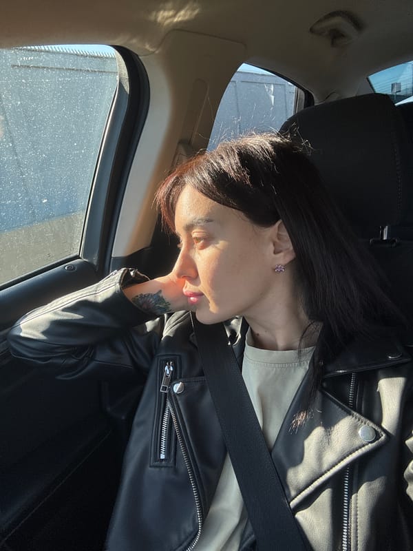 Woman rests in car near Tbilisi monument during highway travel