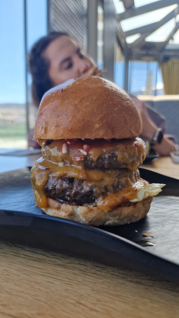 Half-finished double cheeseburger observed on wooden table surface