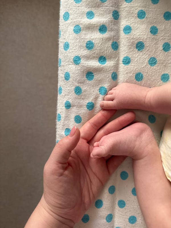 Adult tenderly holds baby's feet in gentle moment
