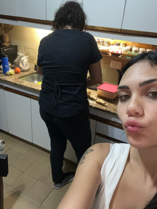 Woman takes kitchen selfie with person in background, Buenos Aires