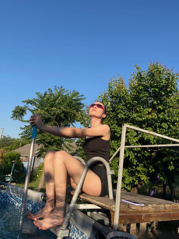 Poolside hang in black swimsuit and red sunglasses