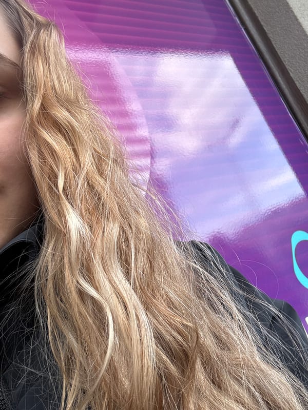Person with blonde hair seen against purple reflective surface