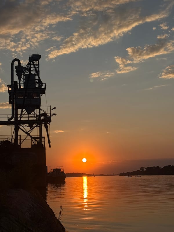 Sunset over Belgrade's riverfront, cranes and calm water