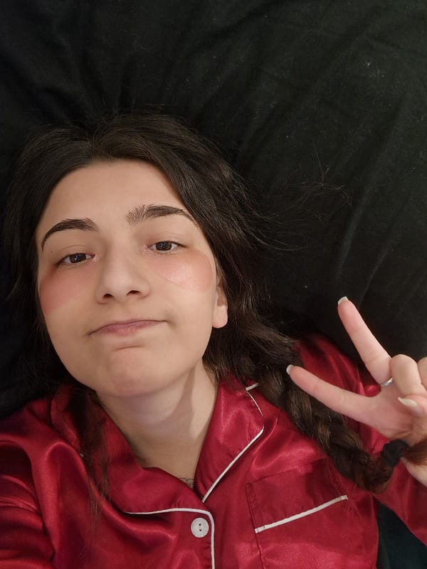 Woman in red pajamas makes peace sign indoors