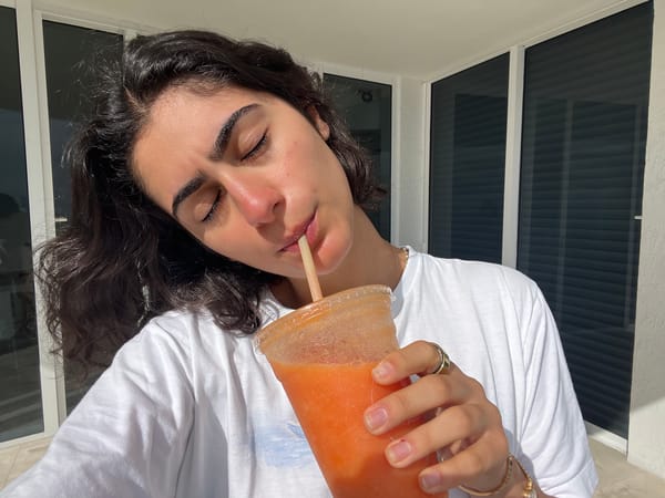Woman enjoys orange drink on Miami Beach high-rise balcony