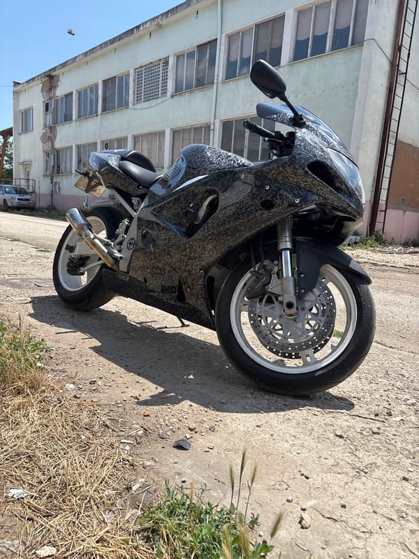 Camo sport bike parked outside weathered industrial building in Pleven